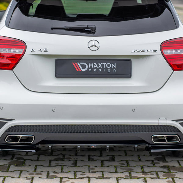 A white Mercedes A 45 AMG car is parked on a cobblestone surface, featuring a Maxton Design rear bumper and dual exhaust outlets.