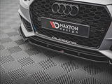 A car's front grille, featuring the Audi logo and honeycomb pattern, rests on a geometric-patterned floor. Text reads 