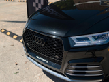 A black car displays a prominent grille with the Audi logo and 