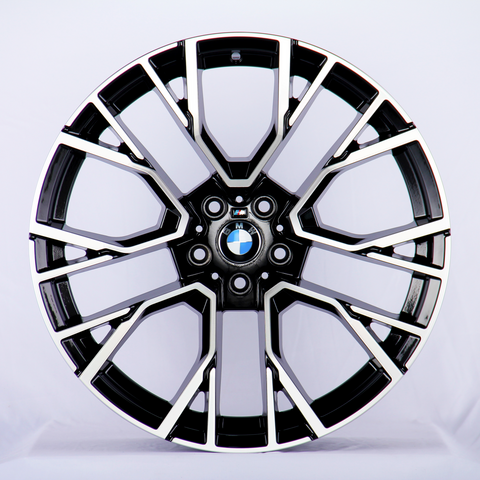 A black and chrome car wheel rim, with intricate geometric patterns, displaying the BMW logo at its center; set against a plain white background.