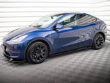A blue electric car is stationary in an indoor garage with patterned flooring and white paneled walls, featuring black wheels and sleek, modern design lines.