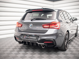 A gray BMW hatchback is parked on a patterned floor in a well-lit, corner room with white walls. The car features dual exhausts and red taillights. Text: 