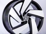 A Volkswagen wheel rim, featuring a sleek black and white design, rests against a neutral white backdrop.