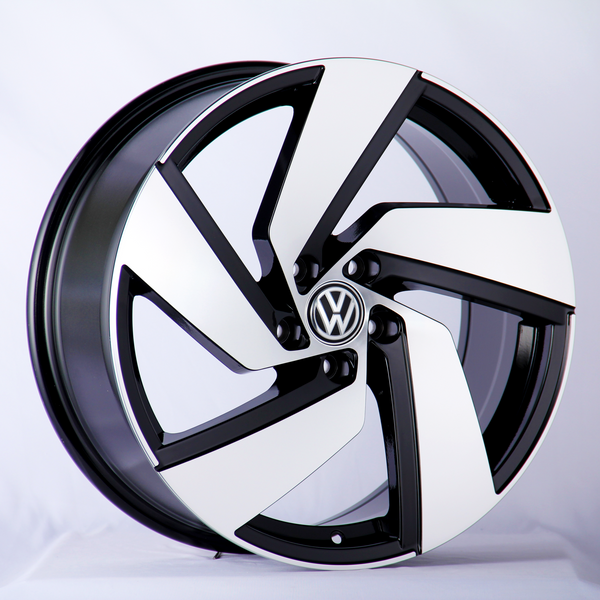 A Volkswagen wheel rim, featuring a sleek black and white design, rests against a neutral white backdrop.