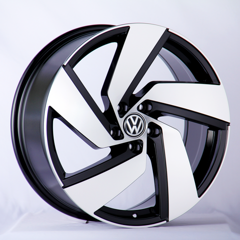 A Volkswagen wheel rim, featuring a sleek black and white design, rests against a neutral white backdrop.