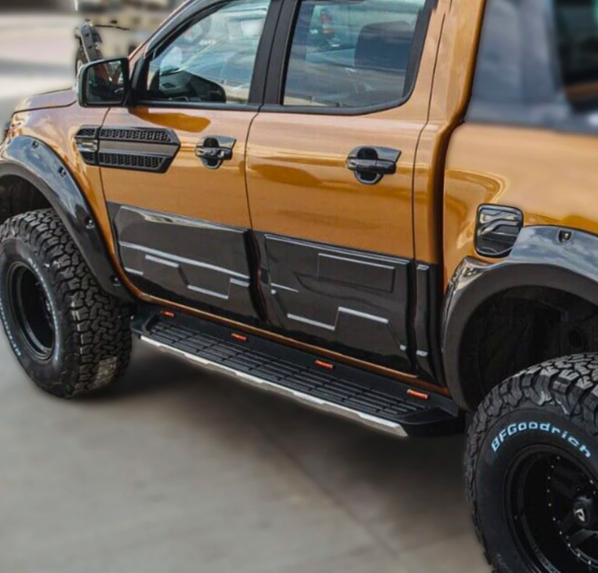 A modified pickup truck, parked, displaying a shiny orange and black exterior with large off-road tires labeled "BFGoodrich" and distinct side steps; situated on a paved surface.