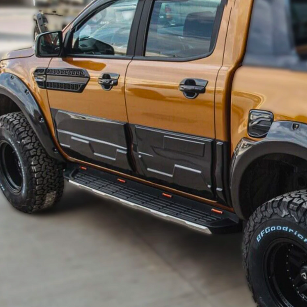 A modified pickup truck, parked, displaying a shiny orange and black exterior with large off-road tires labeled "BFGoodrich" and distinct side steps; situated on a paved surface.