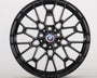 A glossy black, intricately designed car wheel with a central BMW logo and "M" insignia, set against a plain white background.