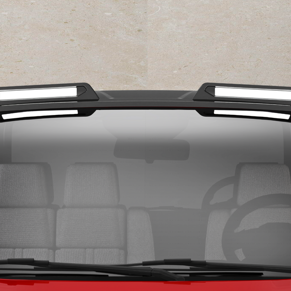 A red vehicle with a black roof features two rectangular, white-highlighted roof racks. The front windshield shows a steering wheel and gray seats inside the car, against a concrete background.