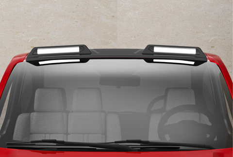 A red vehicle with a black roof features two rectangular, white-highlighted roof racks. The front windshield shows a steering wheel and gray seats inside the car, against a concrete background.