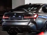 A sleek BMW car is parked in a dimly lit garage with a matte finish, featuring illuminated taillights and a prominent spoiler. The area appears modern and industrial.