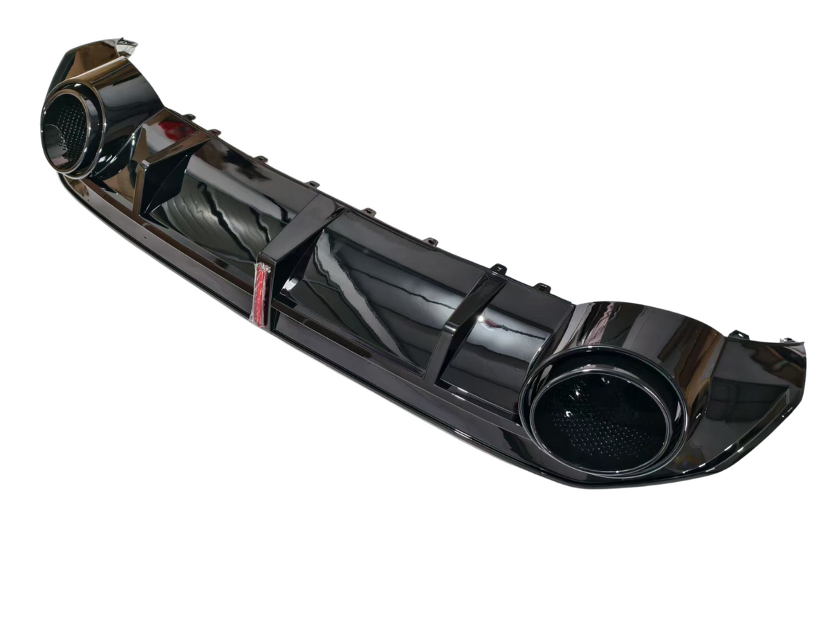 A glossy black car bumper features two circular exhaust outlets and ribbed design details. It is photographed against a plain white background, showcasing its sleek and reflective surface.