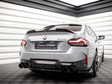 A gray BMW M240i is parked on a checkered floor in a well-lit showroom. The car's rear license plate reads 