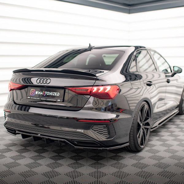 A black Audi car is parked in a well-lit showroom with checkered flooring. The license plate reads "@MAXTONIZED."