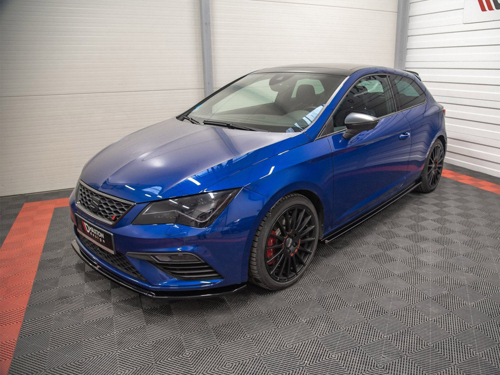 Blue hatchback car parked in a showroom with grey and red checkered flooring; features tinted windows, black alloy wheels, and a front grille. "Maxton Design" text visible on the front plate.