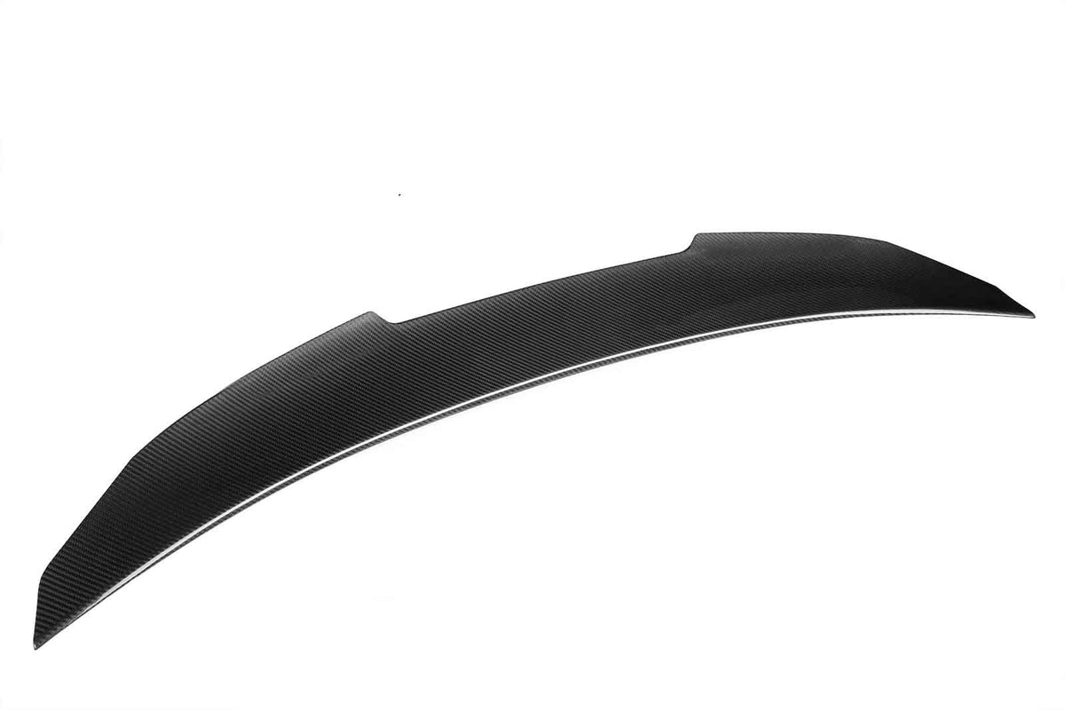 A black carbon fiber car spoiler lies on a plain white background, showcasing its aerodynamic design and textured surface.