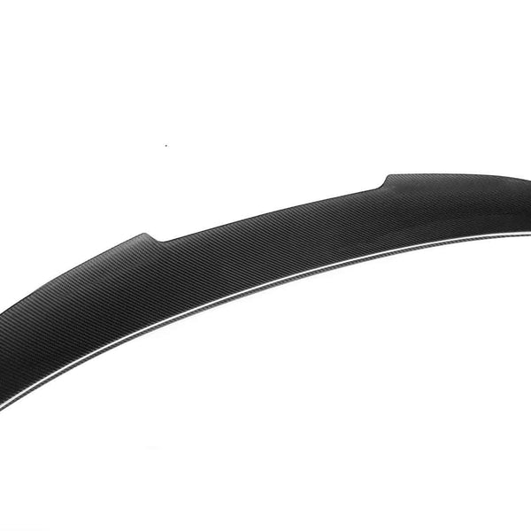 A black carbon fiber car spoiler lies on a plain white background, showcasing its aerodynamic design and textured surface.