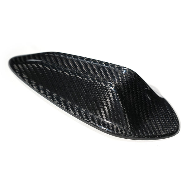 A sleek, black carbon fiber object sits on a white background, showcasing a smooth, aerodynamic shape with a woven texture, possibly designed for vehicle use or aerodynamics.