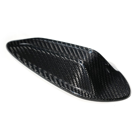 A sleek, black carbon fiber object sits on a white background, showcasing a smooth, aerodynamic shape with a woven texture, possibly designed for vehicle use or aerodynamics.