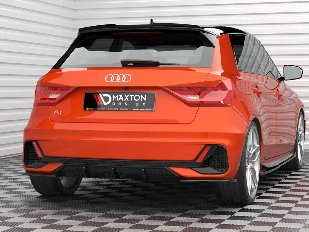 Car sits stationary, showcasing a vibrant orange rear with distinct taillights and sporty accents. License plate reads "MAXTON design." Background consists of white paneled walls and patterned flooring.