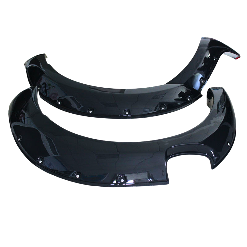 Two glossy black automotive fender flares lie on a plain white surface, with smooth curved shapes and evenly spaced attachment holes along their edges.