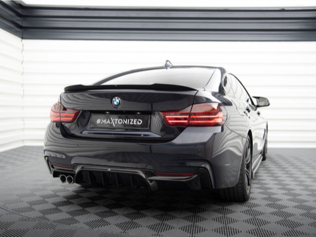 A sleek black BMW is parked in a modern, well-lit garage. The car, seen from the rear, features the text "#MAXTONIZED" on its license plate.