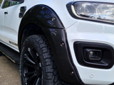 A white pickup truck features a black carbon fiber wheel arch, chunky off-road tires, and 