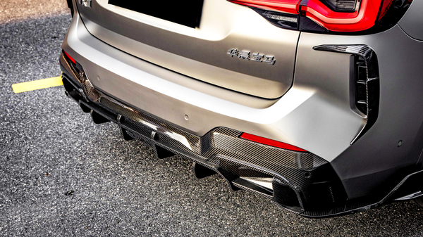 Car rear with a carbon fiber diffuser, parked on asphalt. "华晨宝马" text on the back, red taillights illuminated, set in bright daylight.