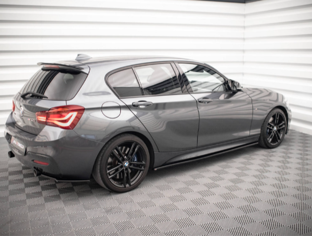 A gray hatchback car is parked in a well-lit, modern showroom with checkered flooring and white panel walls.