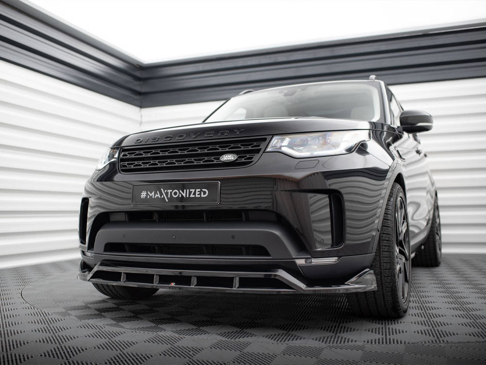 A black SUV, labeled "DISCOVERY," is parked in a modern garage. The license plate reads "#MAXTONIZED." The environment has checkered flooring and striped walls.