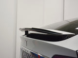 A car's rear end features a black spoiler on a white polished surface, with 