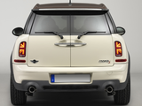A cream-colored car, viewed from the rear, displays distinctive taillights and dual exhausts against a plain backdrop. The 