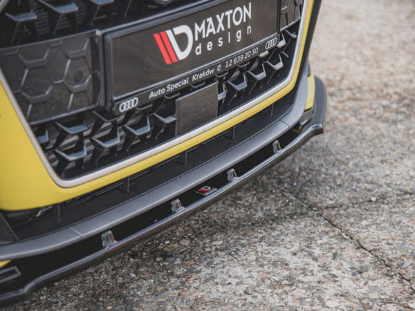 Car front bumper with a Maxton design plate featuring Audi's logo; it rests on a textured, concrete surface. Text: "MAXTON design," "Auto Special Kraków," and "12 639 20 50."