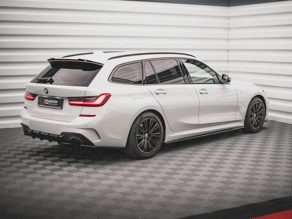 A white BMW station wagon is parked on a checkered floor in a bright, modern showroom. The license plate reads "DARITON DESIGN."