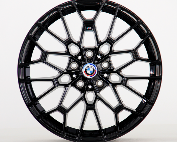 A glossy black alloy wheel with intricate geometric design, displaying the BMW emblem at its center. It is standing upright against a plain white background.