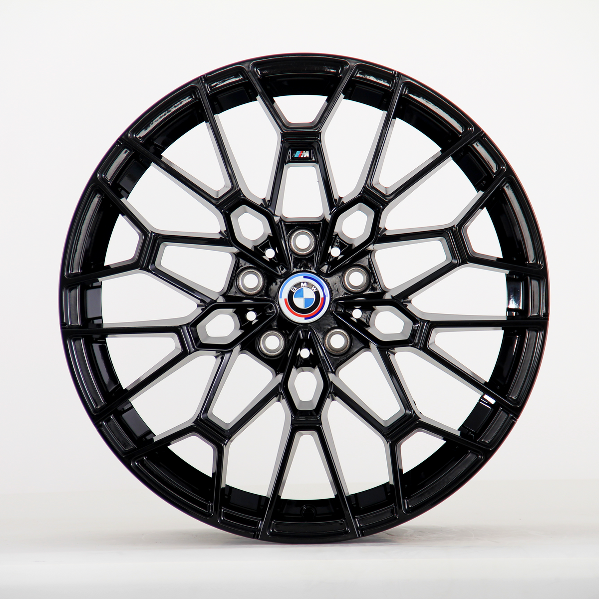 A glossy black alloy wheel with intricate geometric design, displaying the BMW emblem at its center. It is standing upright against a plain white background.