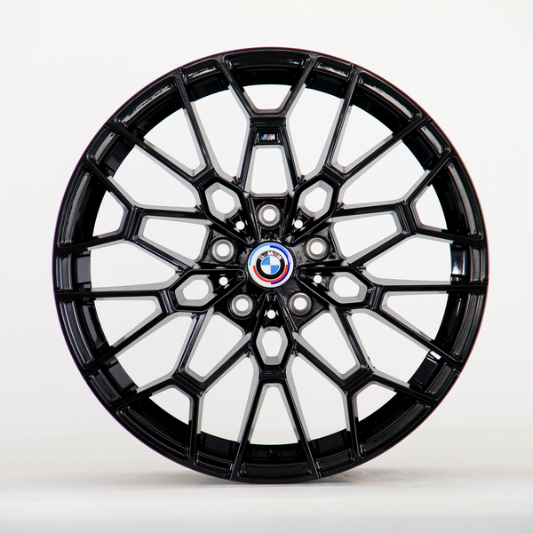 A glossy black alloy wheel with intricate geometric design, displaying the BMW emblem at its center. It is standing upright against a plain white background.
