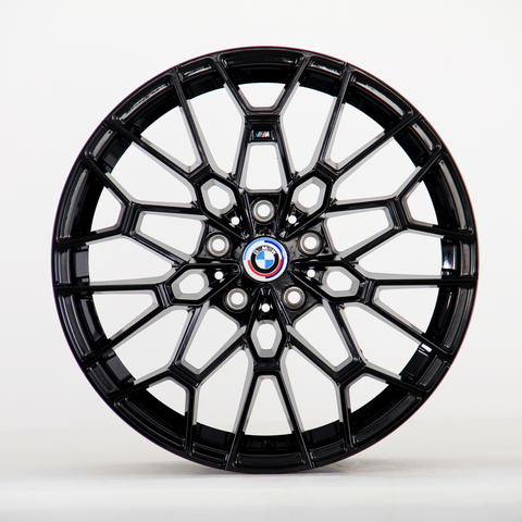 A glossy black alloy wheel with intricate geometric design, displaying the BMW emblem at its center. It is standing upright against a plain white background.