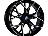 A black and metallic car wheel rim features a geometric spoke design, displaying a centrally placed BMW logo. The rim is isolated on a white background.