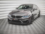 A sleek, gray BMW sports car with illuminated headlights sits on a checkered floor in a bright, white-paneled room. A license plate reads: 