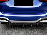 A blue car's rear with a carbon fiber diffuser and four exhaust pipes, parked on an asphalt surface. The license plate area is obscured.
