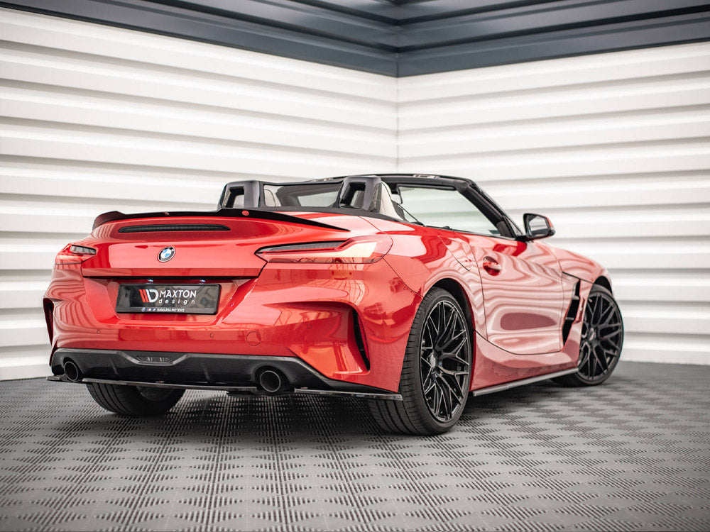 A red convertible sports car is parked indoors on a textured floor. It features sleek aerodynamic lines and black alloy wheels. License plate shows "Maxton Design."