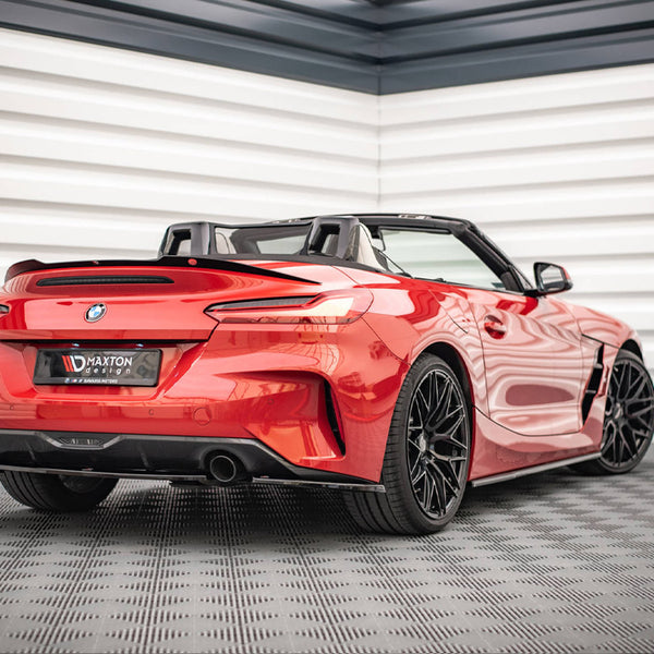 A red convertible sports car is parked indoors on a textured floor. It features sleek aerodynamic lines and black alloy wheels. License plate shows "Maxton Design."