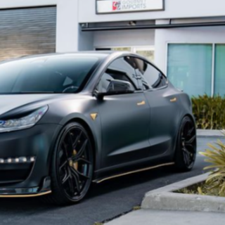 A sleek, black car with tinted windows is parked in front of a modern building. The environment is urban and features minimal landscaping. A sign above reads "GVE London."