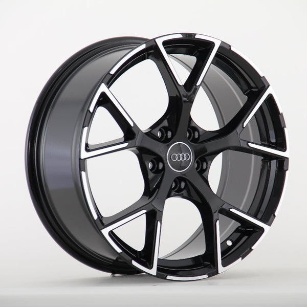 A black and silver alloy wheel with a five-spoke design, prominently featuring the Audi logo in the center, is displayed against a plain white background.
