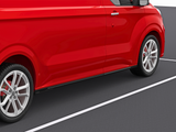 A red van is parked in a parking space, with visible white lines on the asphalt. The focus is on the side and wheels, highlighting its sleek design and shiny finish.