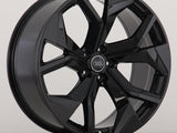 A glossy black alloy wheel with a seven-spoke design prominently displays an Audi logo at its center, positioned against a plain, neutral background.