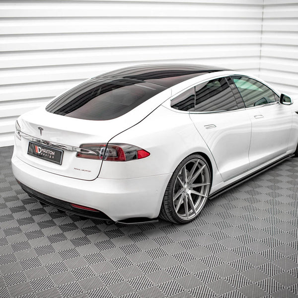 A white car with a sleek design is parked on a patterned floor in a modern showroom with white paneled walls. The license plate reads "MAXTON design."