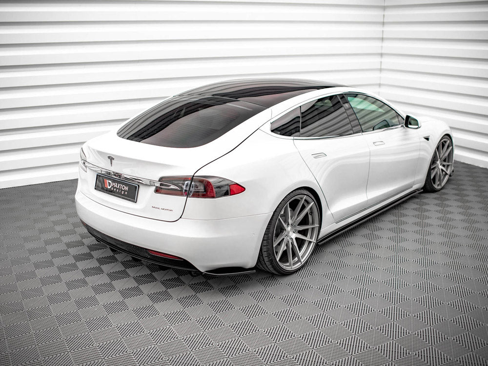 A white car with a sleek design is parked on a patterned floor in a modern showroom with white paneled walls. The license plate reads "MAXTON design."