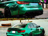 A green sports car is parked, displaying dual exhausts and black wheels. It is situated near water with a city backdrop. Text includes 